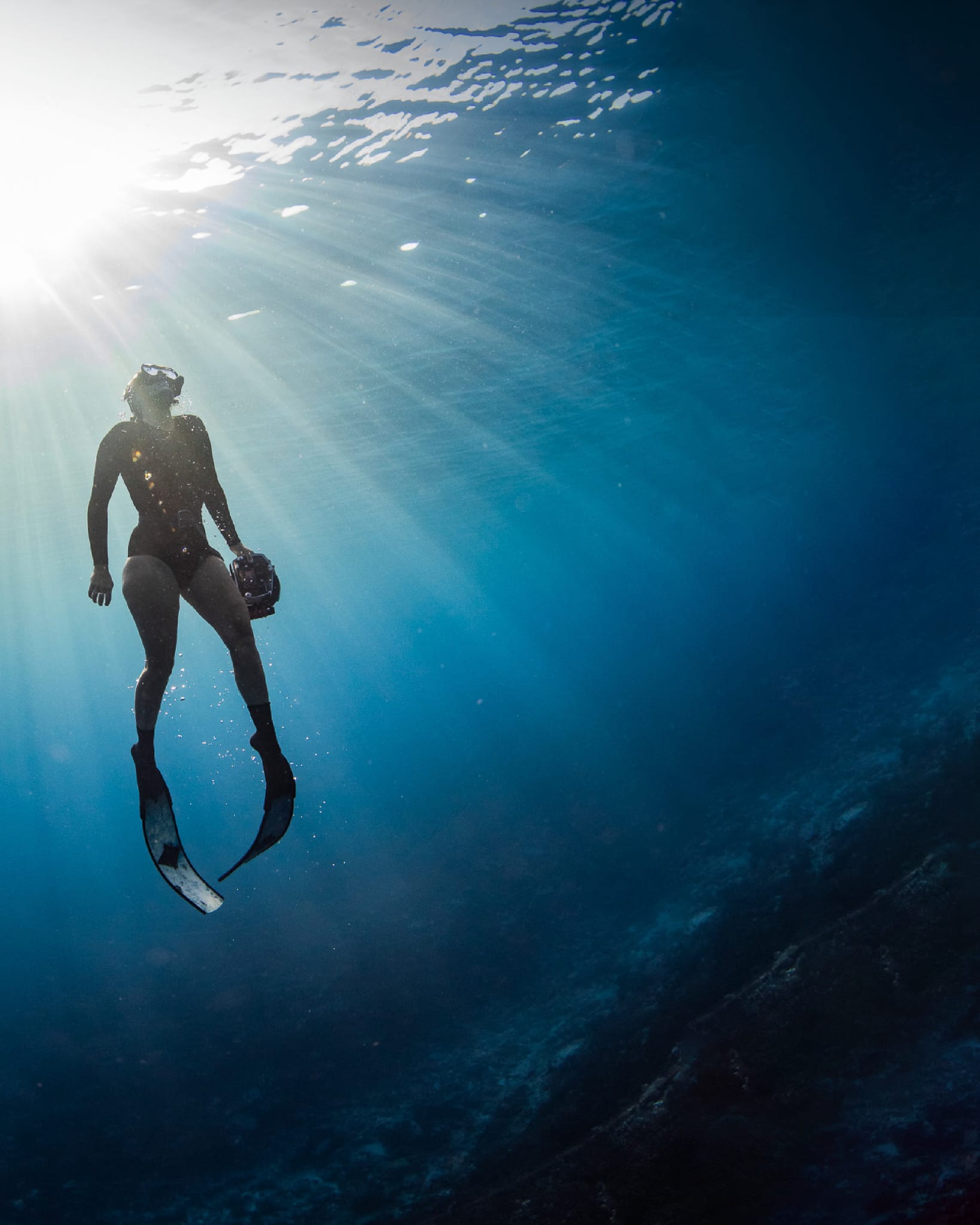 Freediver descending through sunlit water at Cook Island